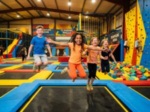 Kids jumping mid-air at an indoor trampoline and adventure park.